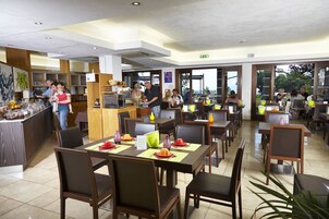 Un comedor amplio con varias mesas y sillas, un mostrador de buffet y vistas al exterior.