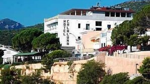 Hotel anomenat "CALALU HOTEL" amb vista al mar i muntanyes al fons.