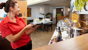 Zona de petit esmorzar d'hotel amb menjar a la barra, incloent diversos aliments i condiments.