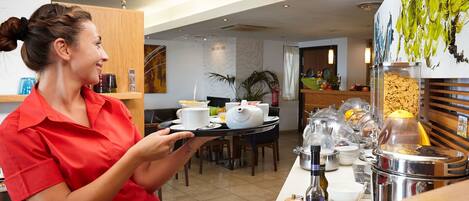 Zona de desayuno de hotel con sistema de bufé, que incluye diversos alimentos y condimentos.