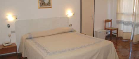 A bedroom with a bed, bedside tables, a chair, a wardrobe, and a painting on the wall.