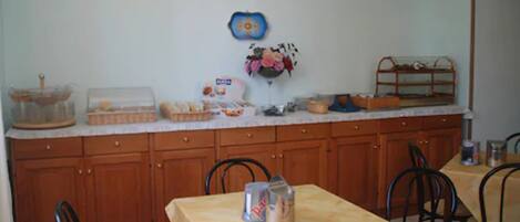Una cocina con armarios de madera, una mesa de comedor, sillas y varios electrodomésticos y utensilios.