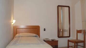 A bedroom with a bed, a nightstand, a chair, a mirror, and an air conditioning unit.