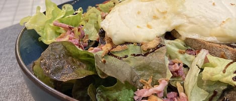 A bowl of salad with various ingredients, including lettuce, tomatoes, and croutons, placed on a table in a restaurant setting.