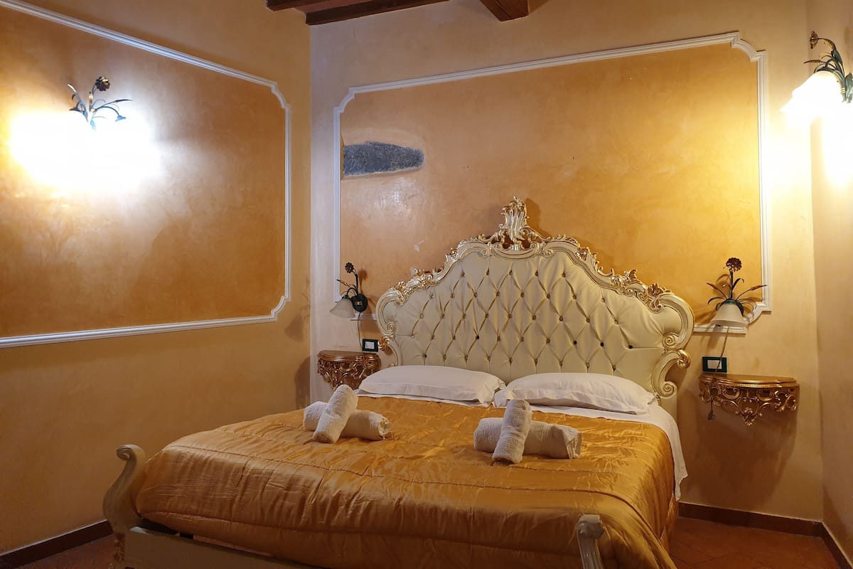 A room with a large bed, ornate headboard, and two bedside lamps.