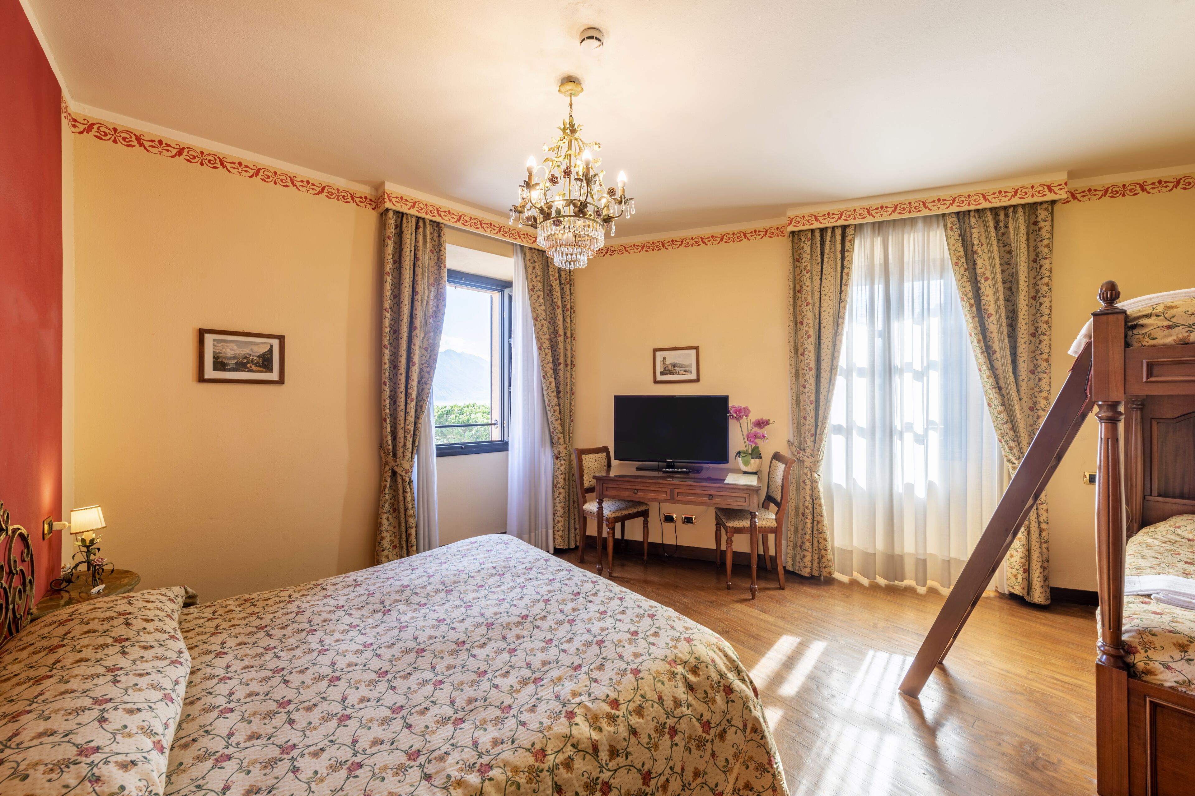 A bedroom with a bed, a desk with a television, and a window with curtains.