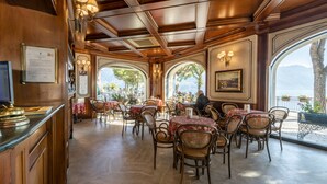 Um restaurante com painéis de madeira, lustres e mesas com toalhas vermelhas.