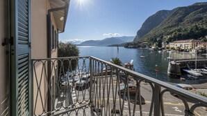 Uma varanda com vista para um lago, barcos e montanhas.