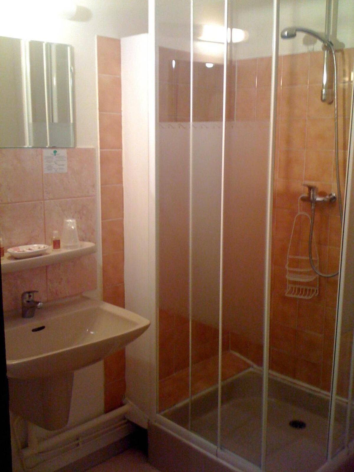 Un baño con ducha de vidrio, lavamanos y espejo.