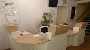 A reception desk area with a plan of the hotel layout on the wall, a clock, and a staircase in the background.