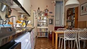 Una cocina con suelo a cuadros, una mesa de comedor con sillas y una estantería llena de libros.