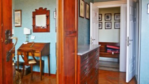 Una habitación con un escritorio de madera, un aparador y un banco con maletas.