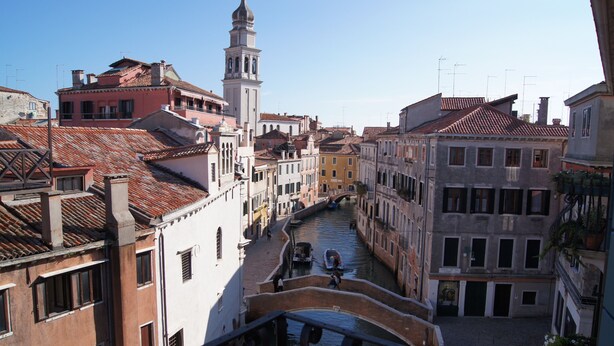 Un canal flanqueado por edificios, un puente y una torre al fondo.