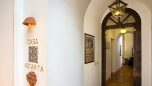 A hallway with a sign reading "CASA ASTARITA," a decorative wall piece, and a patterned floor. - Casa Astarita (Sorrento)