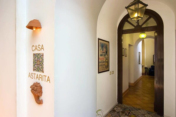 Un pasillo con un letrero que dice "CASA ASTARITA", un adorno de pared y un piso estampado.
