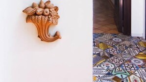 A hallway with a tiled floor, a wall-mounted light fixture, and a decorative tile with the text "CASA ASTARITA". - Casa Astarita (Sorrento)