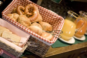A breakfast buffet with bread, pretzels, and juice. - Biohotel Bavaria (Garmisch-Partenkirchen)