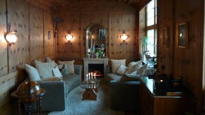A cozy living room with wooden walls, a fireplace, and a comfortable seating area with sofas and a coffee table. - Hotel Roter Hahn - Bed & Breakfast (Garmisch-Partenkirchen)