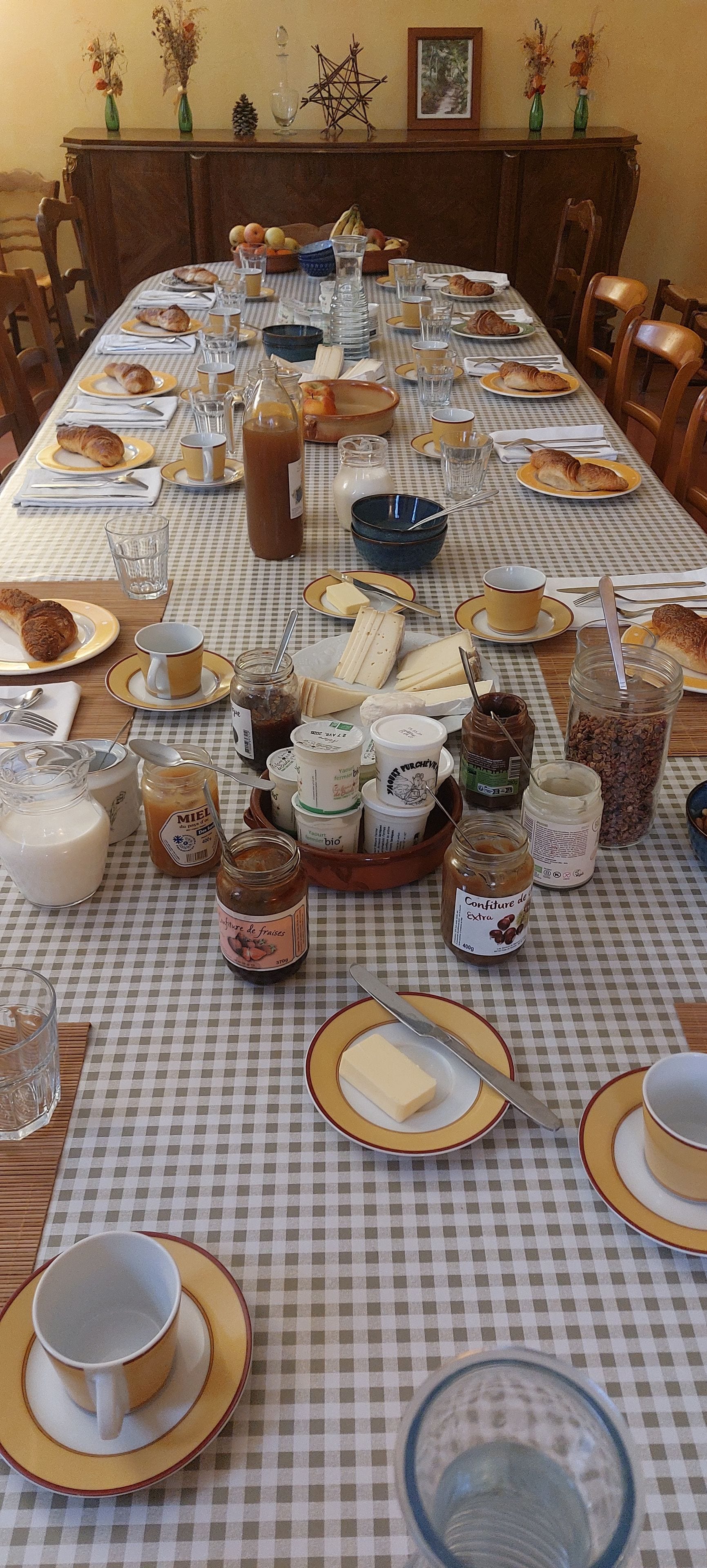 A dining table set with plates, glasses, and various food items, suggesting a meal is being prepared or served.