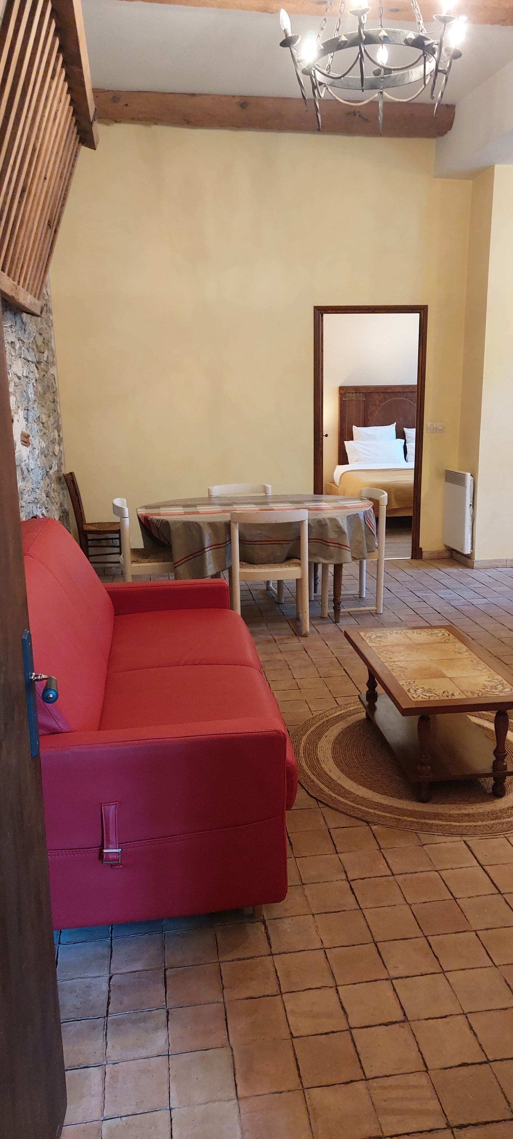 Una sala de estar con un sofá rojo, una mesa de centro de madera y una araña.