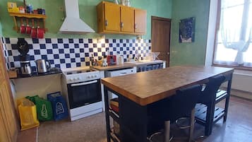 Een keuken met een fornuis, oven en een bar met krukken.
