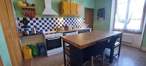 Een keuken met een fornuis, oven en een bar met krukken.