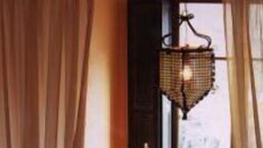 A cozy room with a bed, a small table, and a window with curtains.