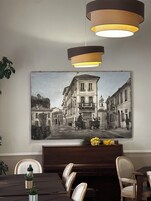 A dining area with a table, chairs, a bench, a wall-mounted painting of a street scene, and pendant lighting.