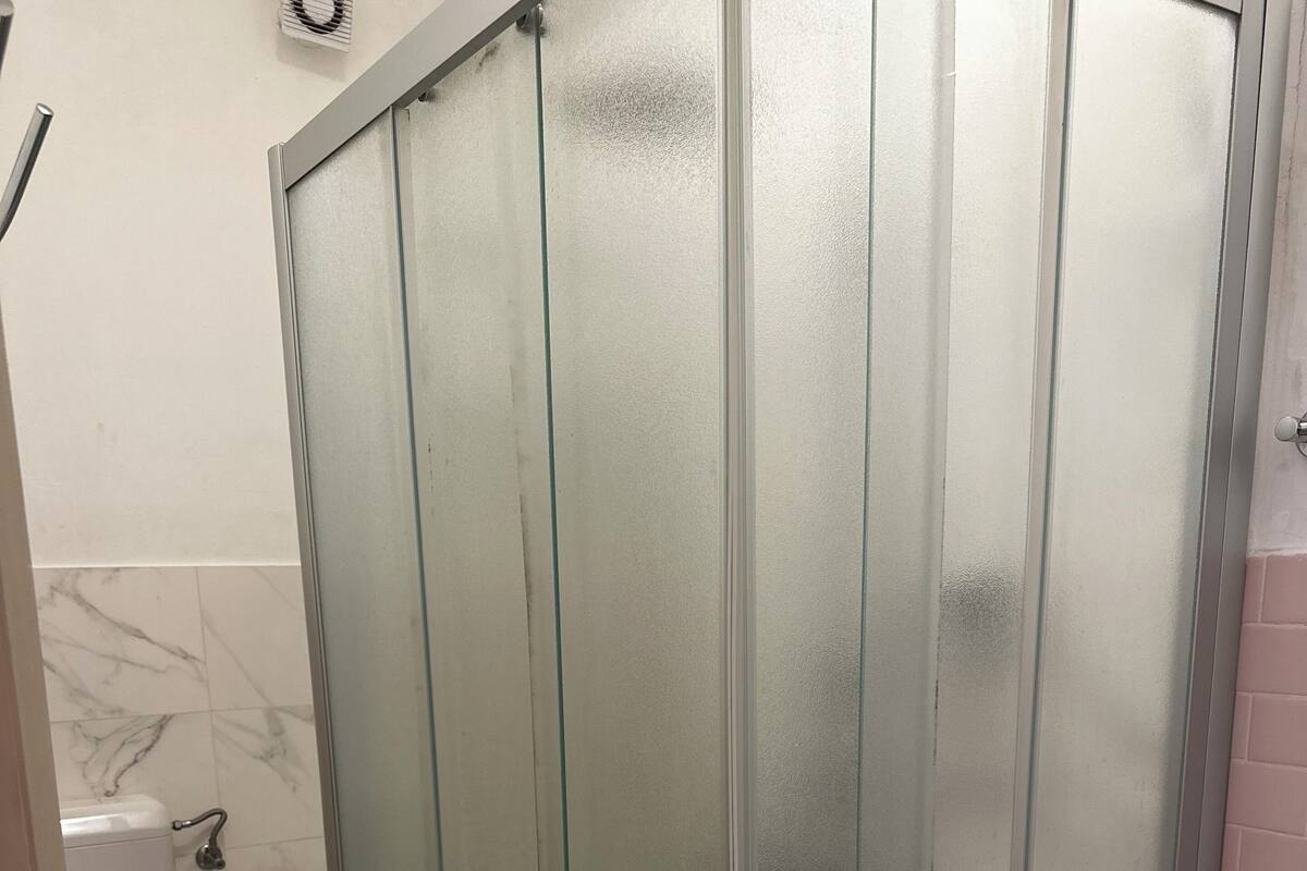 Ein Badezimmer mit Duschkabine, Toilette und einer Toilettenpapierrolle auf einem Handtuch.