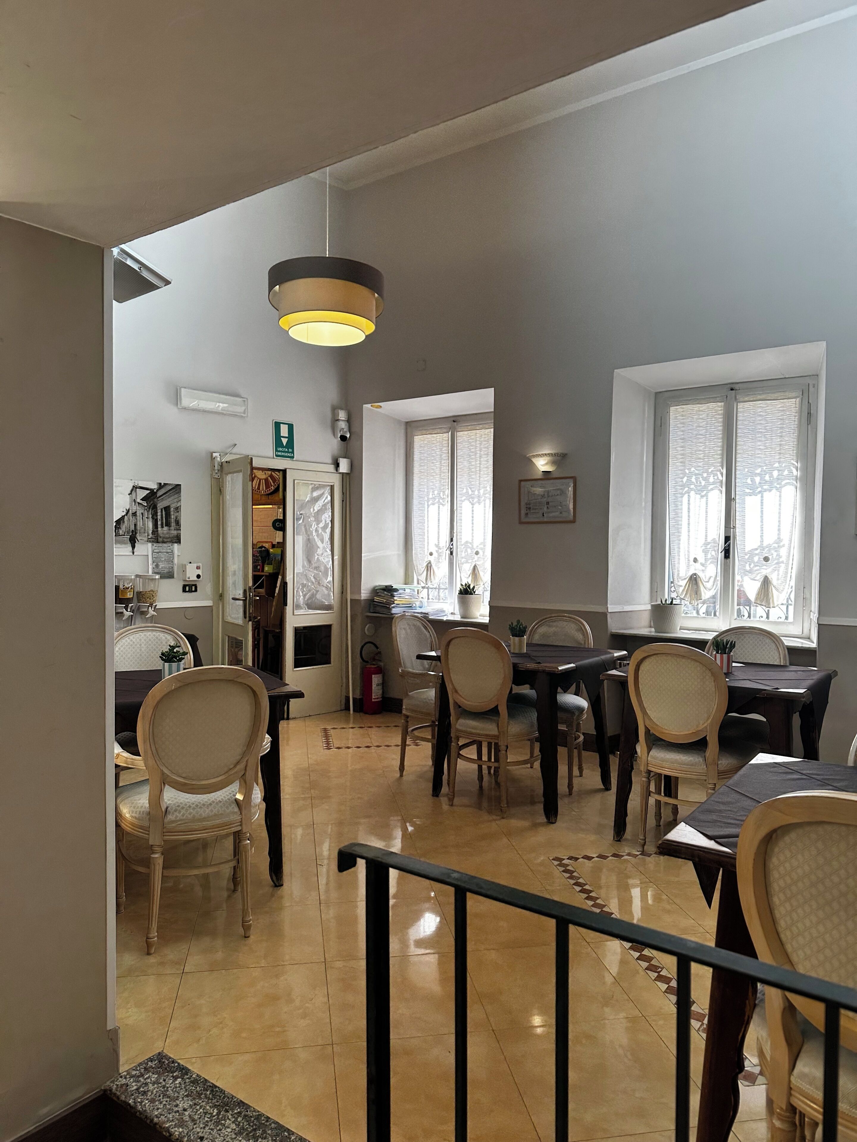 Un comedor con techo alto, una araña y vistas a la calle a través de una puerta.