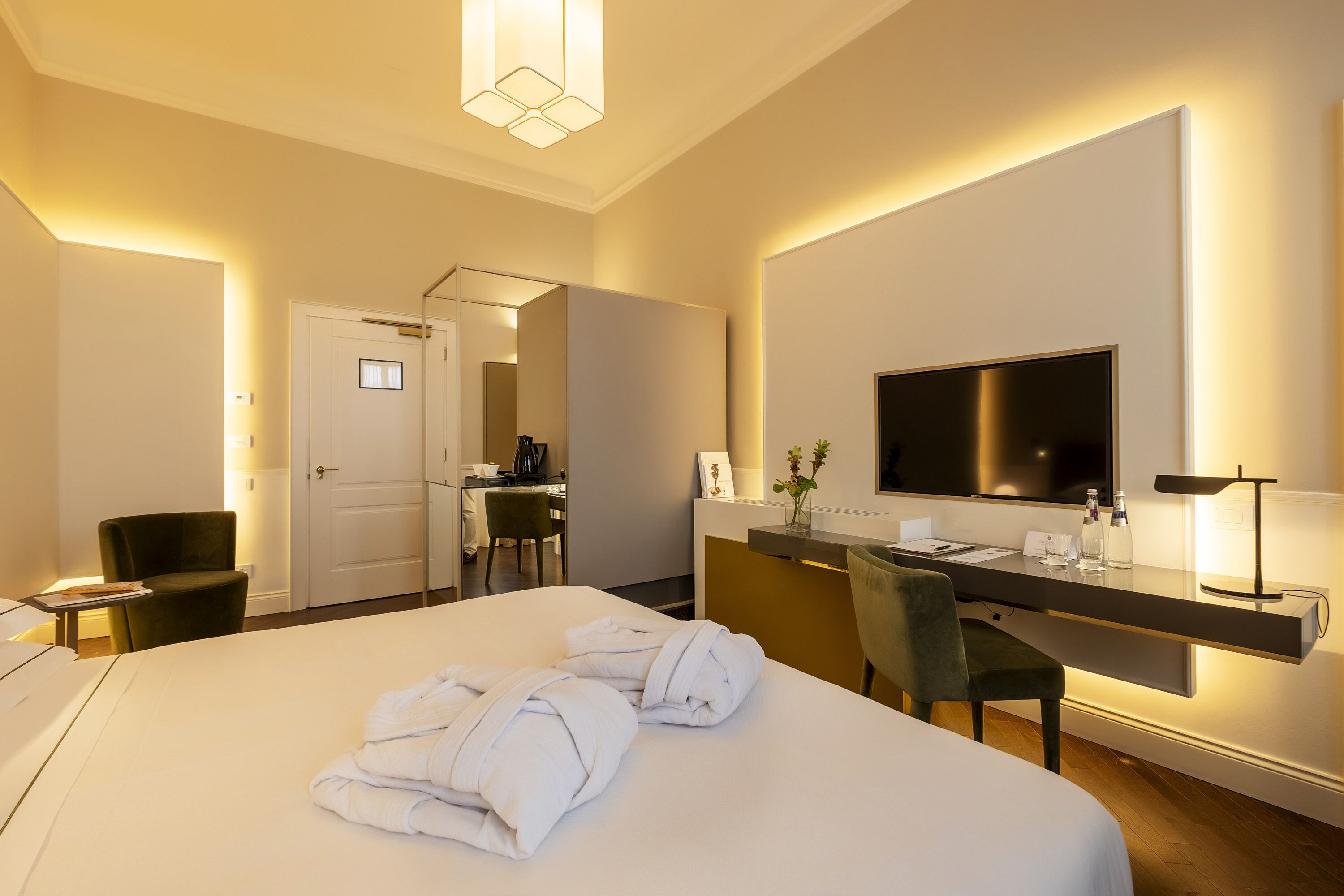 A hotel room with a large bed, a desk with a chair, a TV, and a mirror.