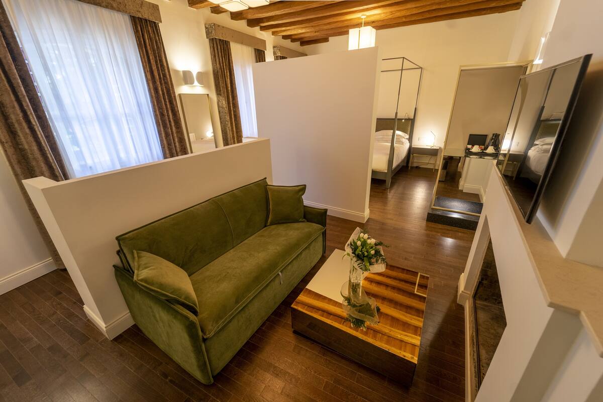 A modern living room with a green sofa, a wooden coffee table, and a large mirror.