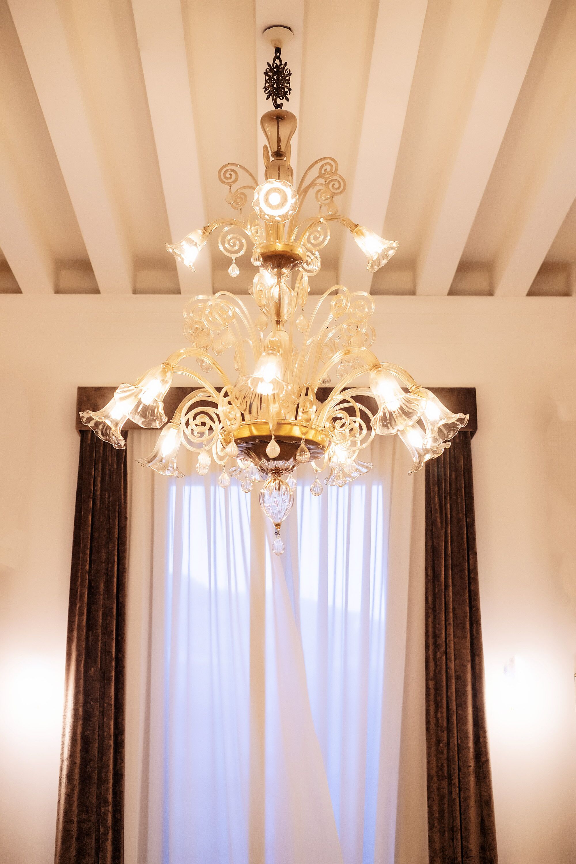 Un lustre composé de plusieurs luminaires suspendus à un plafond orné d’un motif décoratif.