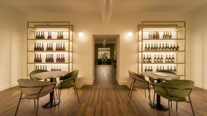 A modern interior with two round tables and green chairs, flanked by illuminated wine racks. - Hotel Villa Soligo - Small Luxury Hotels of the World (Farra di Soligo)
