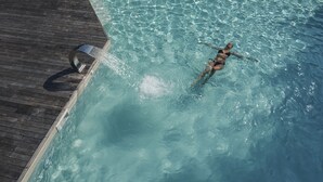 A person swimming in a clear pool with a wooden deck and a lounge chair. - Hotel Villa Soligo - Small Luxury Hotels of the World (Farra di Soligo)