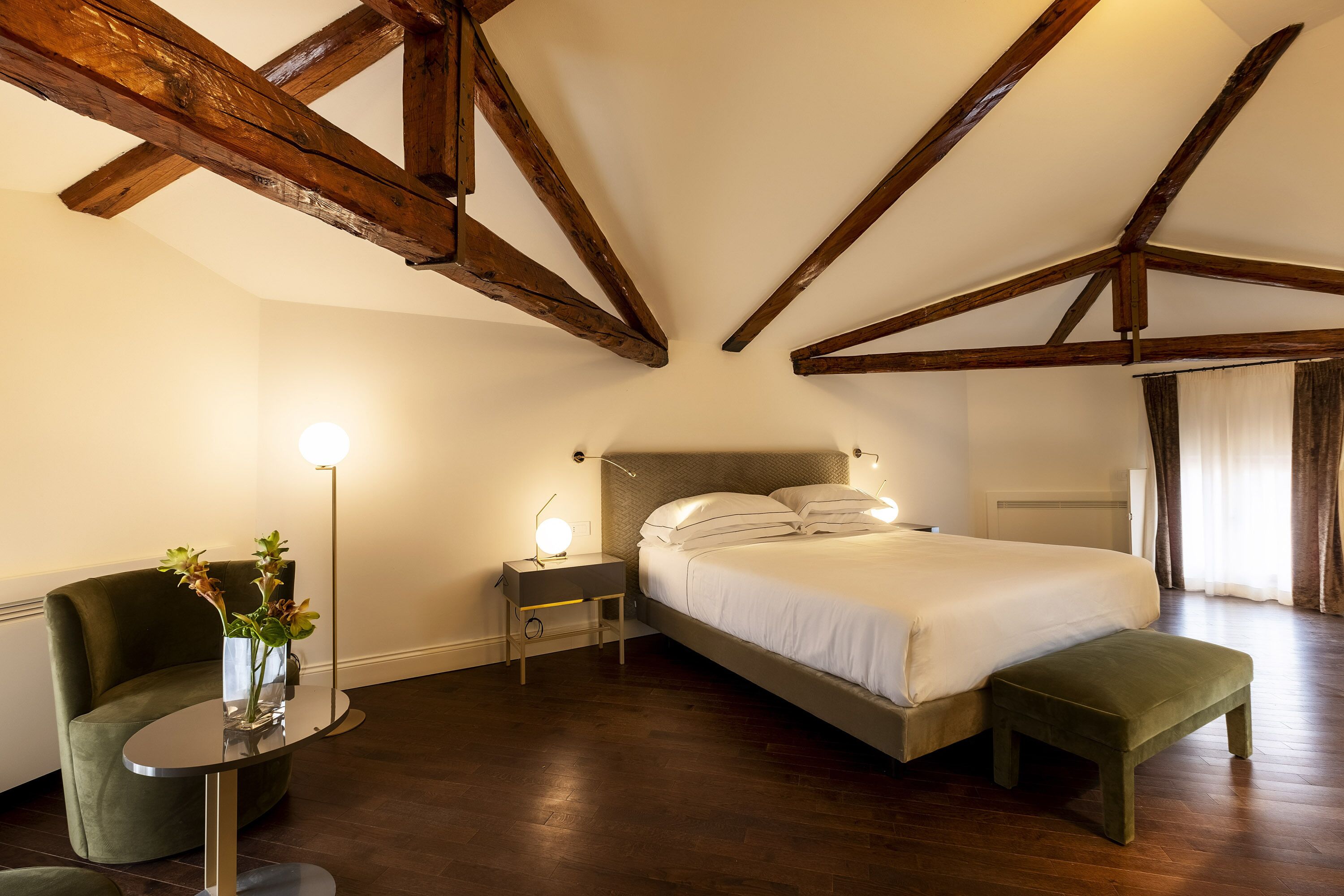Quarto com cama, mesa de cabeceira, abajur e uma cadeira.