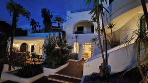 Un edificio moderno con un cortile interno, che include una scala, palme e un ingresso ben illuminato.