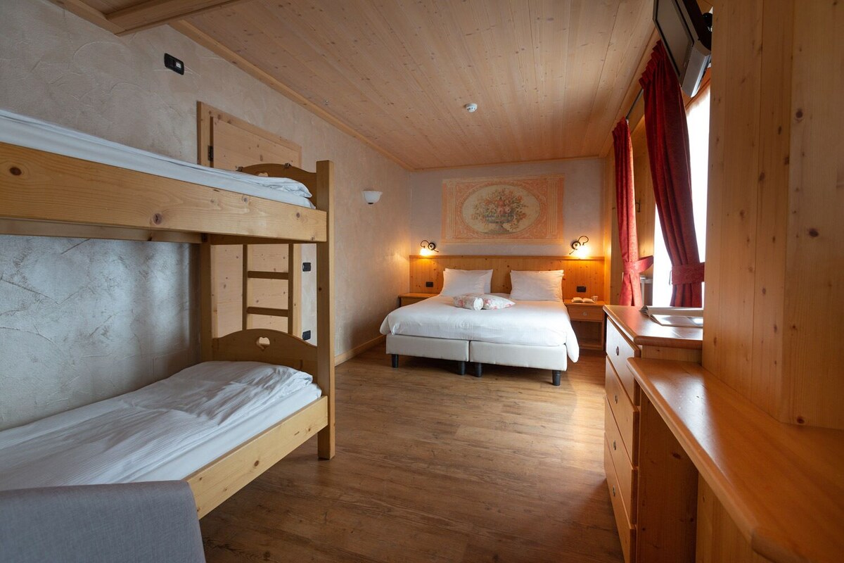 Dormitorio con literas de madera, una cama individual, una mesita de noche y un aparador.
