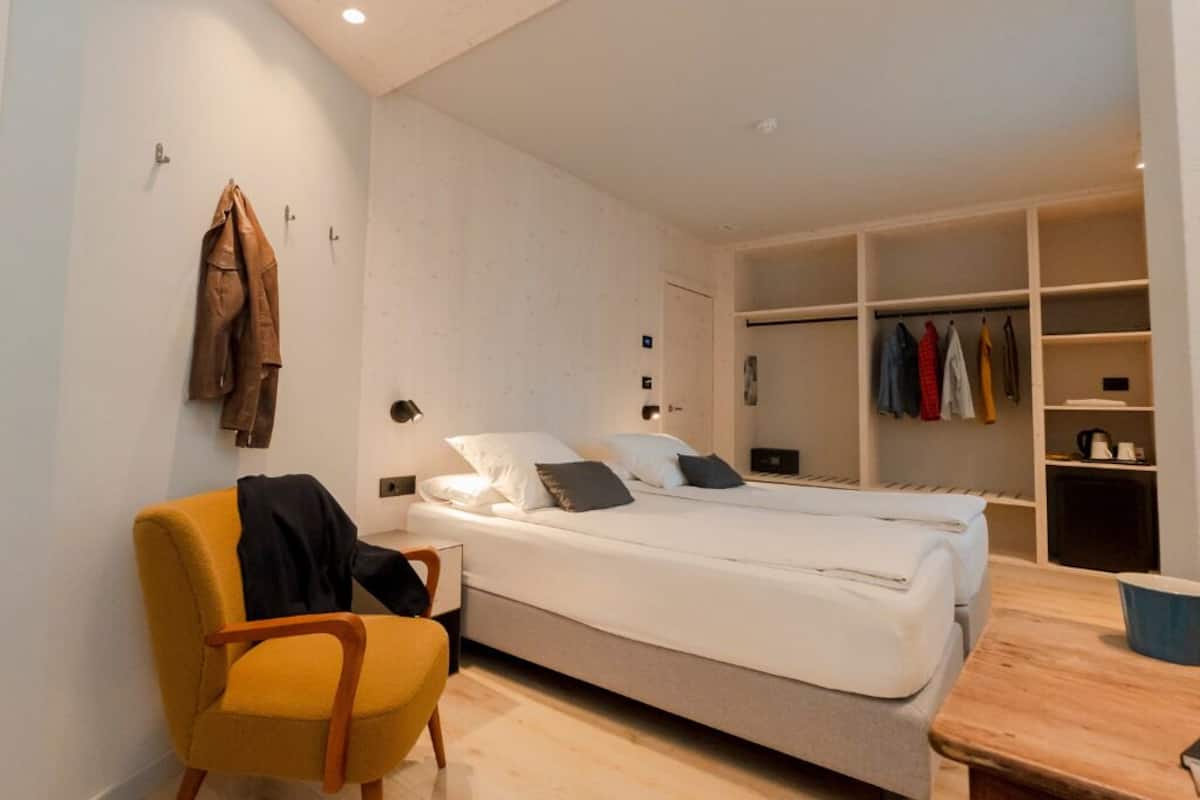 A modern bedroom with a bed, a chair, and a built-in wardrobe.