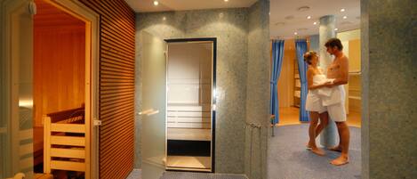 Un baño de hotel con zona de ducha, un banco de madera y suelo de baldosas.