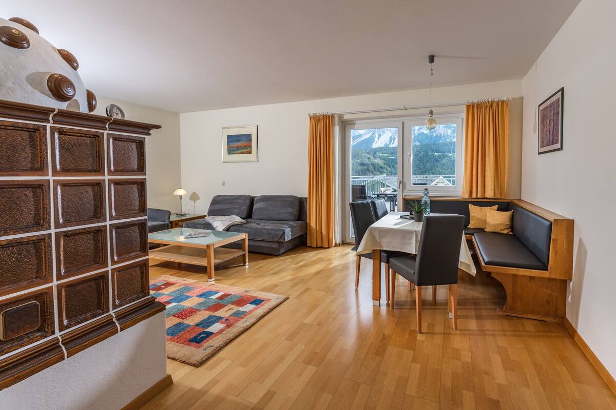 A modern living room with a sofa, a dining table, and a built-in bench.
