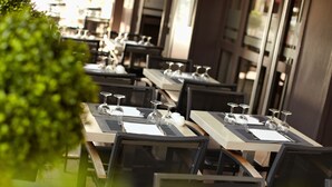 A restaurant with multiple tables set for dining, each with cutlery and wine glasses. - Hôtel Les Negociants (Valence)