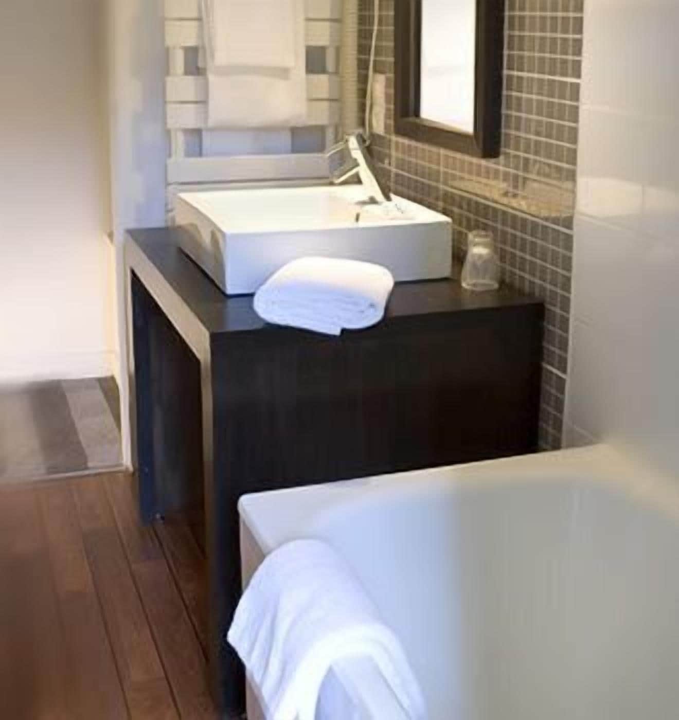 A modern bathroom with a dark countertop, a white sink, and a mirror above it.