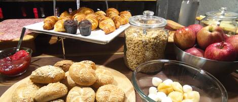 Ein Buffet mit verschiedenen Speisen, darunter Backwaren, Brot und Obst.