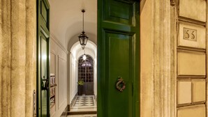 A hallway with a green door, a number 55 sign, and a checkered floor. - Basilio 55 Rome (Rome)