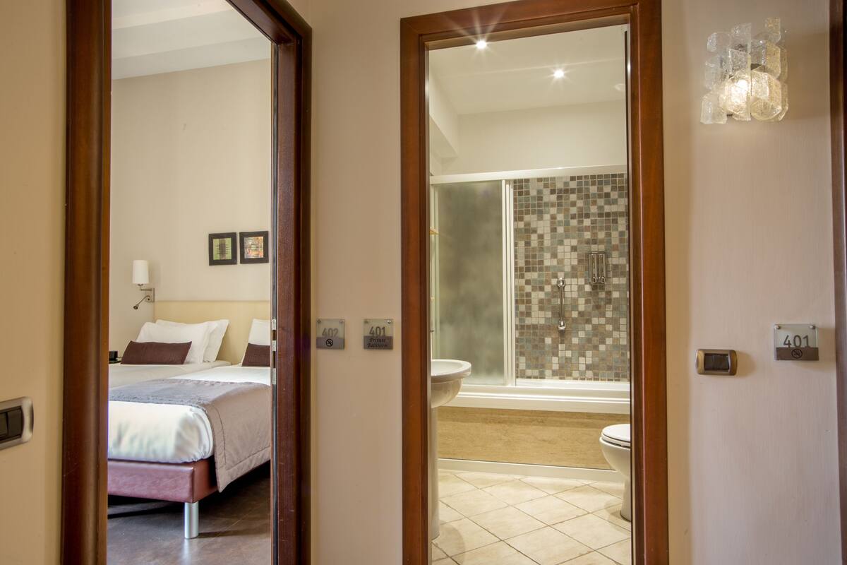 Habitación de hotel con cama, baño con ducha e inodoro.