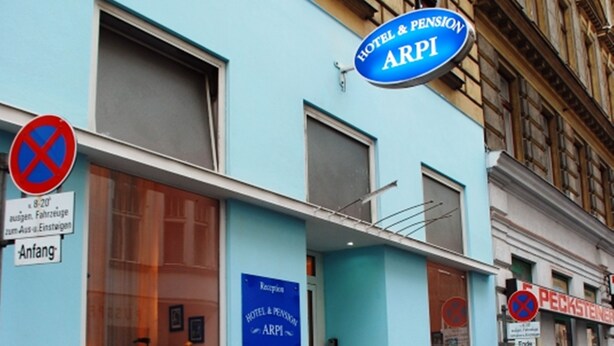 Un hotel llamado ARPI con fachada azul, una zona de recepción y un cartel de 'no estacionamiento'.