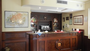 A bar area with a wooden counter, bar stools, a coffee machine, and a shelf with bottles. - Le Terrazze sul Gargano (San Giovanni Rotondo)