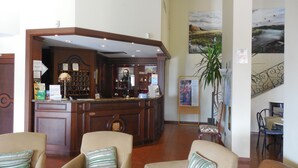 A lobby with a reception desk, seating area, and artwork. - Le Terrazze sul Gargano (San Giovanni Rotondo)