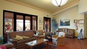 A spacious living room with leather sofas, a coffee table, and a large window with a view of the outdoors. - Le Terrazze sul Gargano (San Giovanni Rotondo)